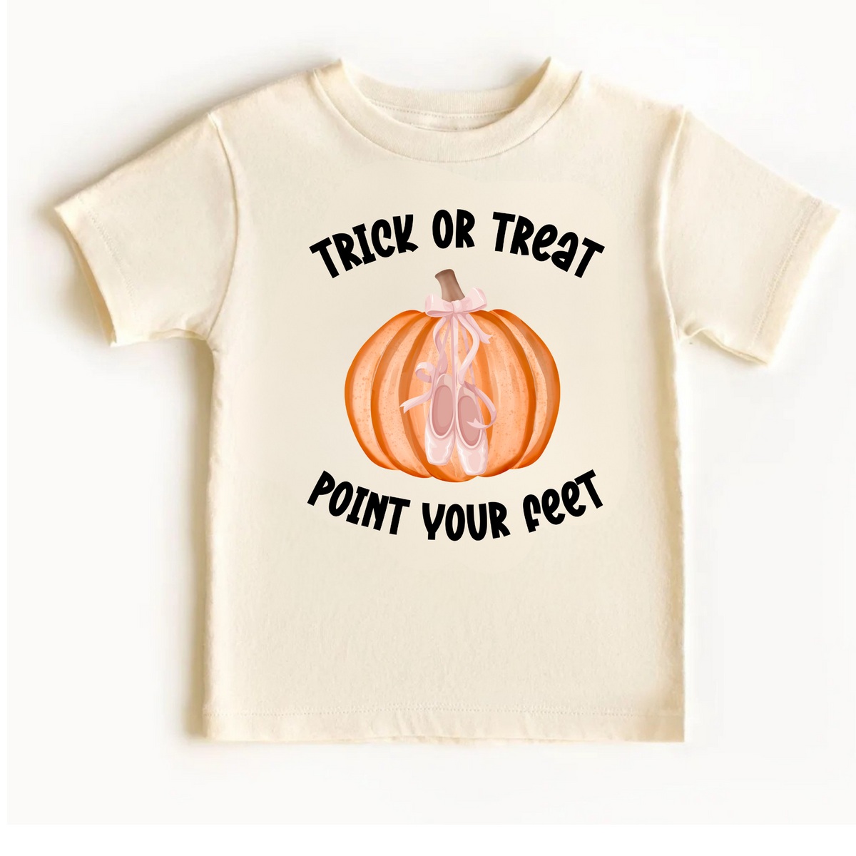 Cream-colored girls Halloween ballet T-shirt flat lay featuring a Trick or Treat Point Your Feet graphic with an orange pumpkin, pink ballet slippers, and a delicate pink bow. Cute ballerina Halloween shirt for girls, perfect for dance class parties, fall outfits, and little ballet lovers.