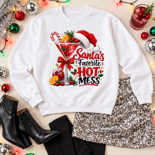 White Santa’s Favorite Hot Mess sweatshirt with a Christmas cocktail graphic, styled with a silver sequin skirt, black boots, ornaments, and holiday lights.