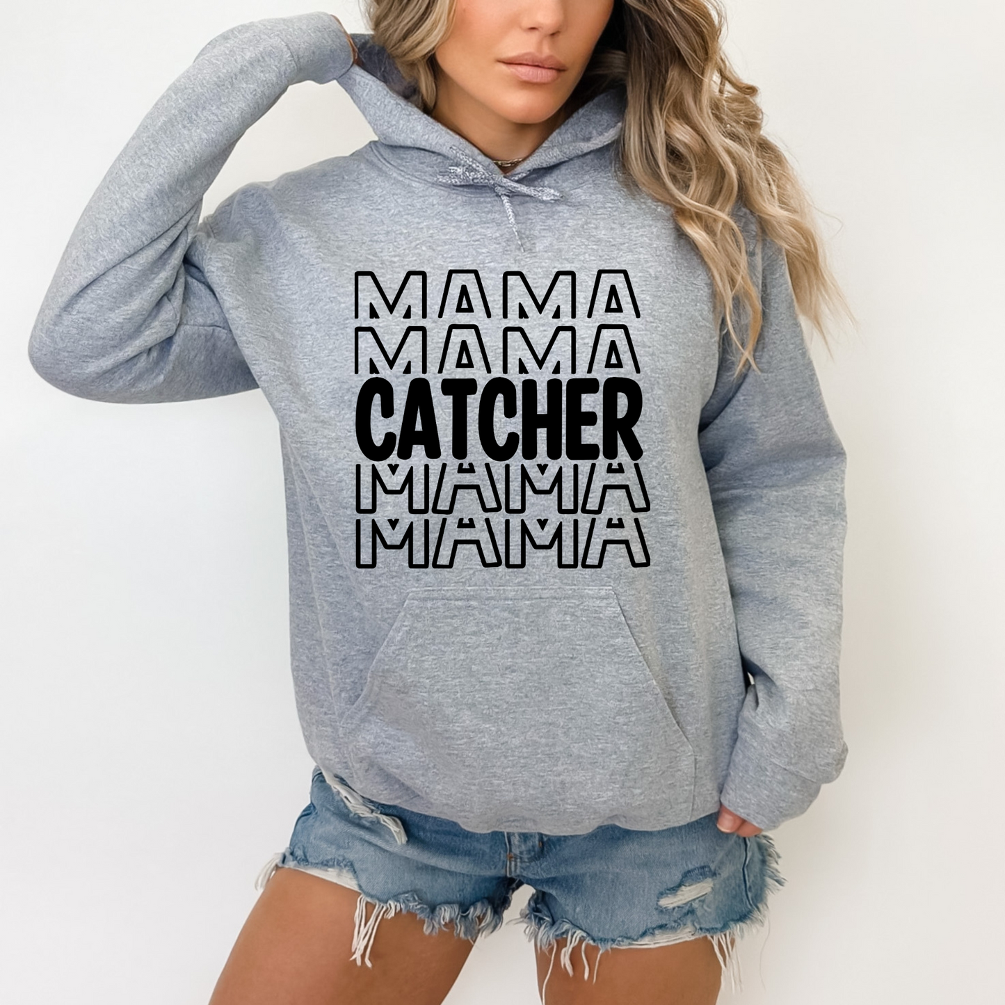 A comfortable and stylish baseball mom hoodie sweatshirt with the words 'Catcher Mama'. This baseball mom outfit is perfect for game day at the baseball game, featuring a cozy design that celebrates the role of a dedicated catcher mom.