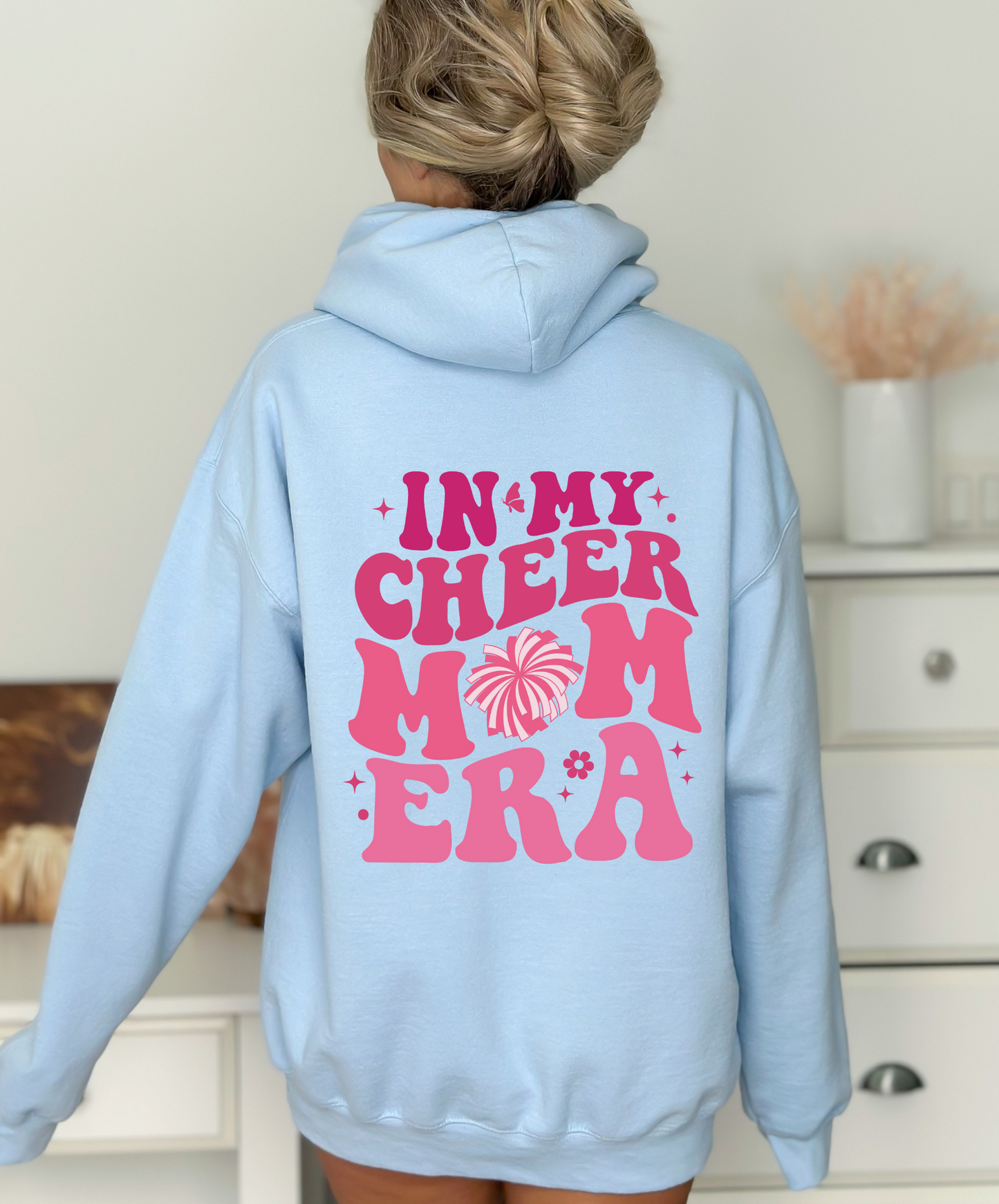 A comfortable hoodie for cheer moms with the text 'In My Cheer Mom Era'. This sweatshirt is ideal for showcasing support for cheerleaders, offering a mix of comfort and style in a humorous design.