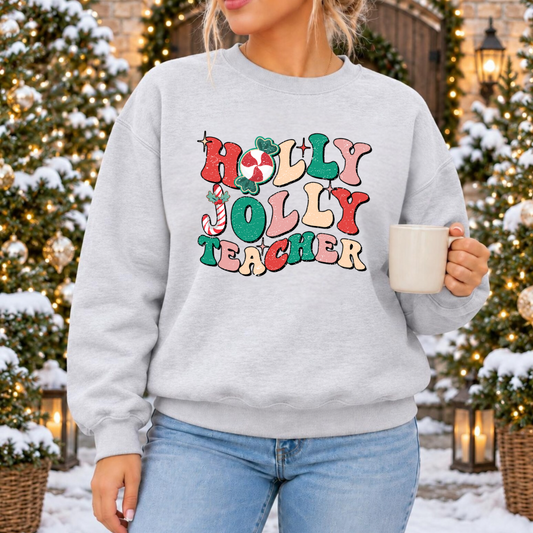 Woman wearing a light gray Holly Jolly Teacher Christmas crewneck sweatshirt with retro pink, red, green and cream lettering, peppermint candy and candy cane details.
