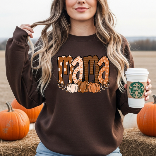 Woman wearing a chocolate brown sweatshirt featuring patterned “Mama” lettering with pumpkins at a pumpkin patch. Cozy fall sweatshirt for women, perfect for pumpkin patch outfits, Thanksgiving, and autumn activities.