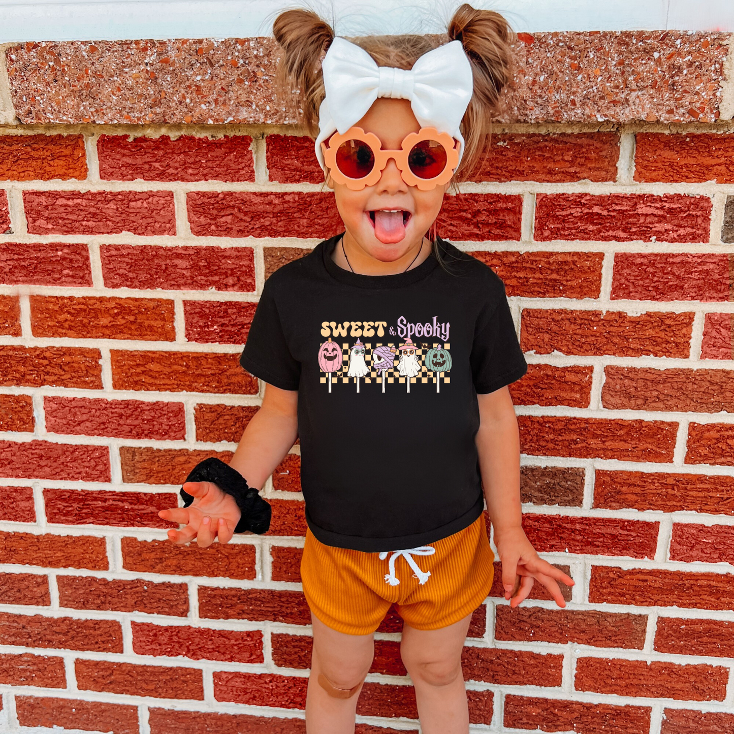 An adorable Halloween shirt for girls with the phrase ',Sweet and Spooky featuring a preppy and playful design. The shirt adds a unique touch to her Halloween outfit, embodying the essence of cute Halloween fun.